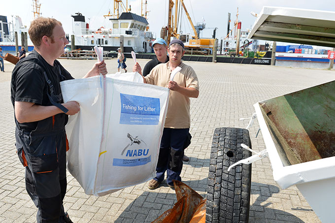 Carsten Noormann (vorne links) entsorgt gefischten Müll im NABU-Container in Norddeich - Foto: NABU/Kim Detloff