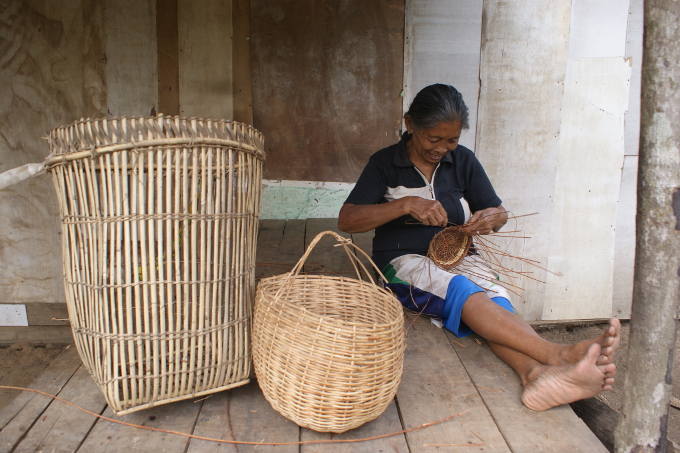 Eine alte Frau aus Harapan beim Körbeflechten